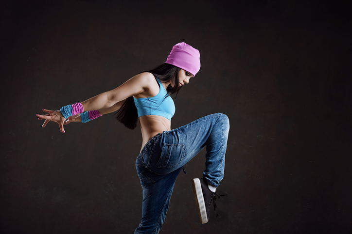 Young sexy woman dancer dancing on black wall background