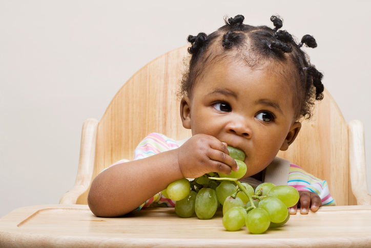 Baby girl eating organic grapes